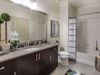 Baths with polished quartz vanities and framed mirrors